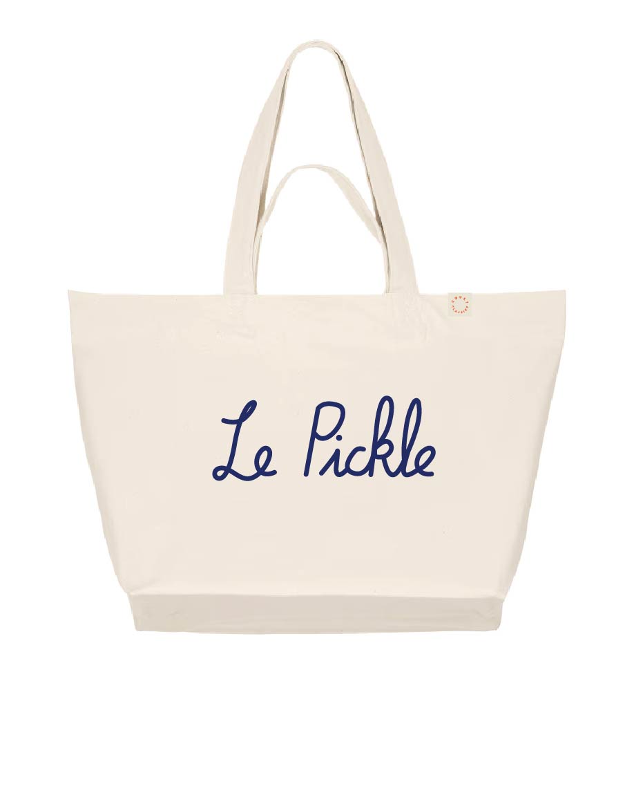 An off-white canvas tote bag with long handles, featuring the text 'Le Pickle' embroidered in navy blue script across the front. A small gold button is visible near the top right handle.